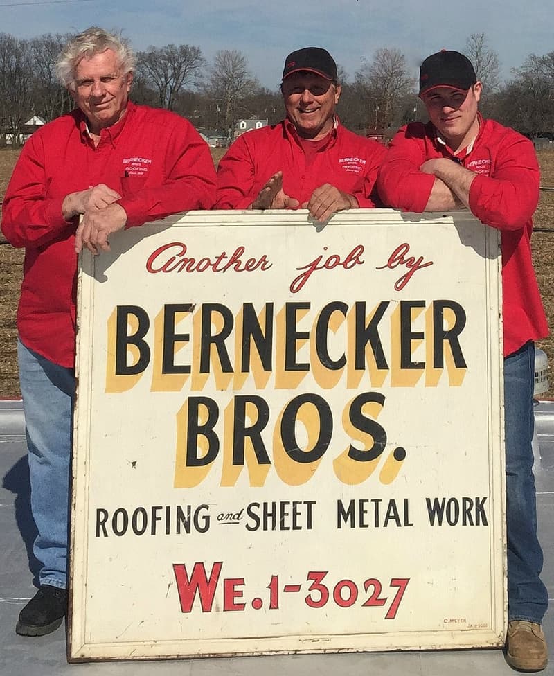 Three crew members holding vintage Bernecker Bros. sign